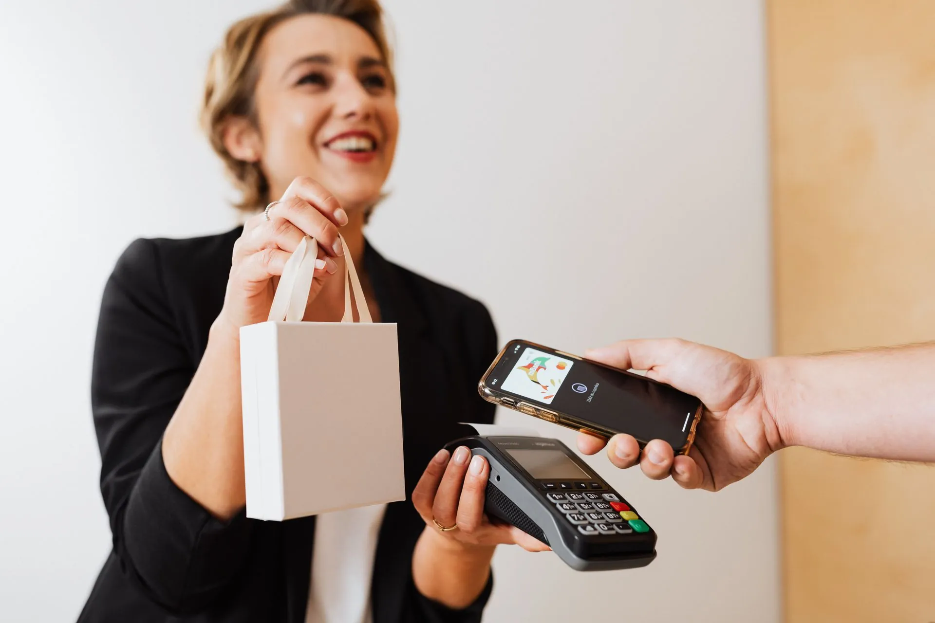 Dueña de un comercio sonriendo mientras un cliente paga acercando su celular