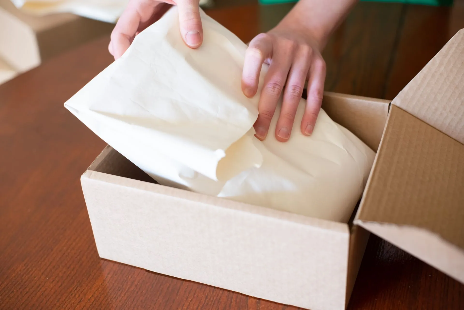 Persona empacando el pedido de una tienda en línea en una caja de cartón